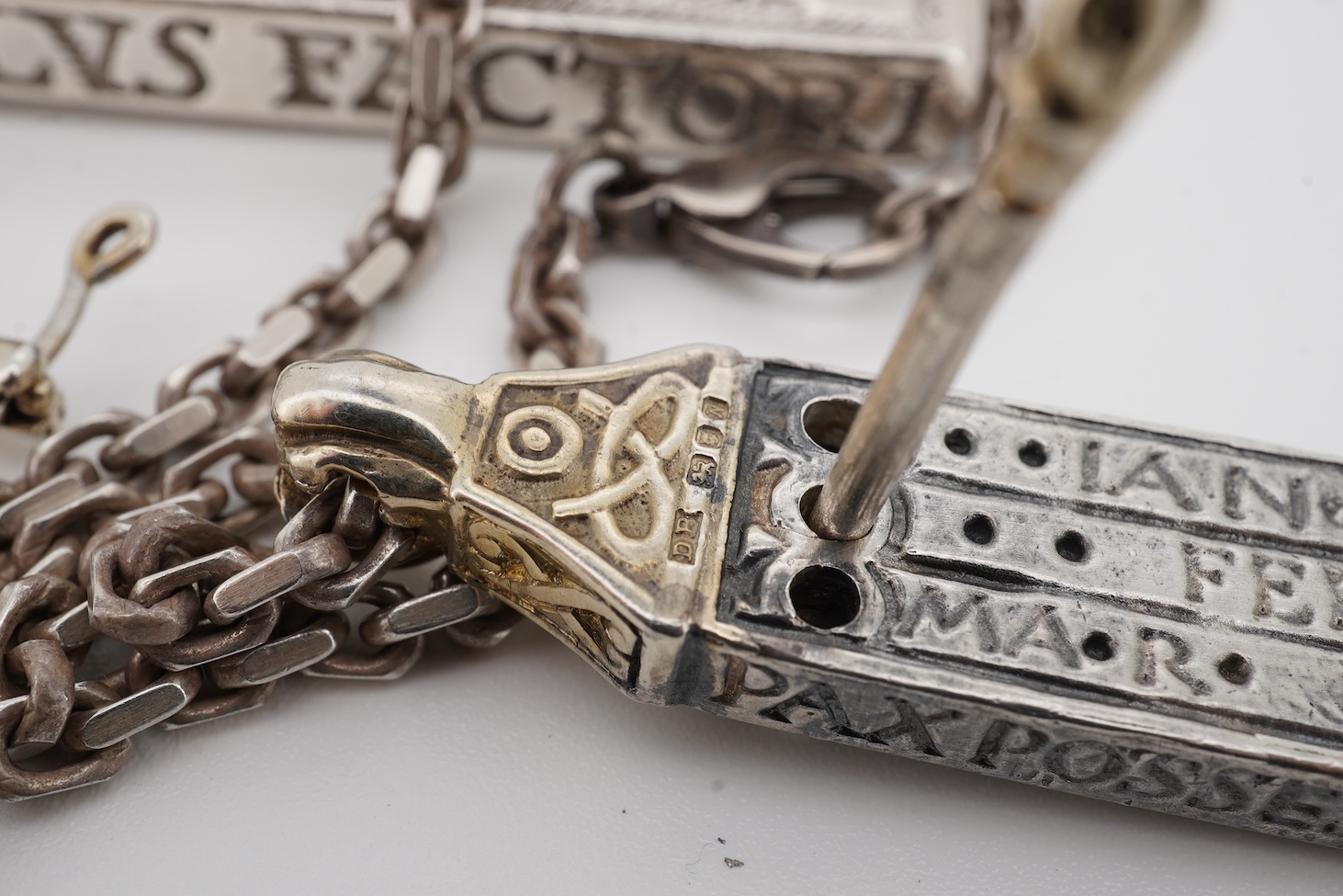 Two modern parcel gilt silver replicas of the Canterbury Pocket Sundial, the larger inset with small emeralds?, maker GF, London, 1975, the smaller later, maker DB, London, 1987, both suspended from a chain.
